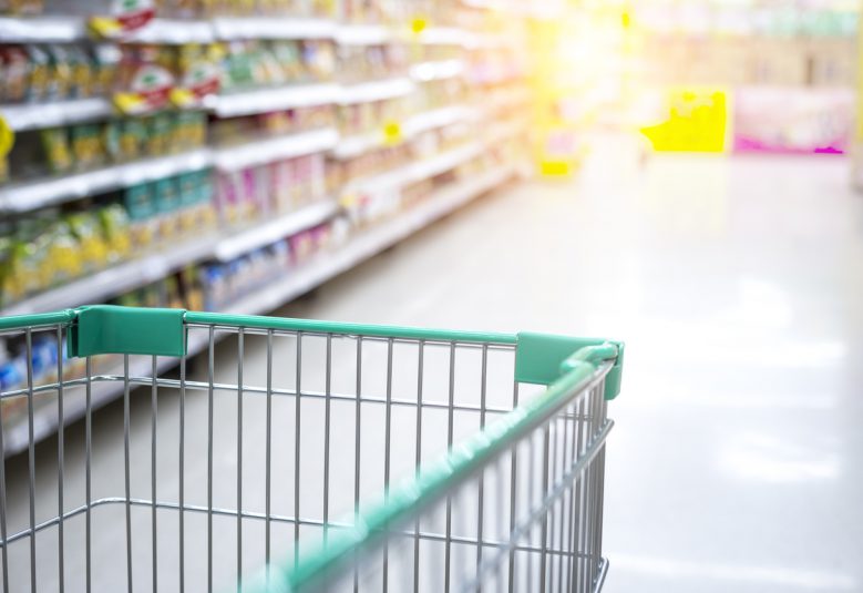 Shopping trolley being pushed down an aisle of a supermarket