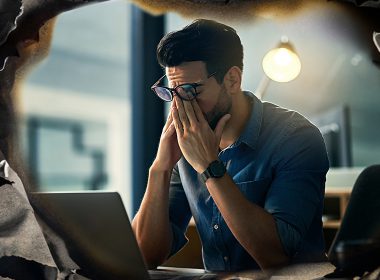 An office worker rubs his eyes after too many long days at work.