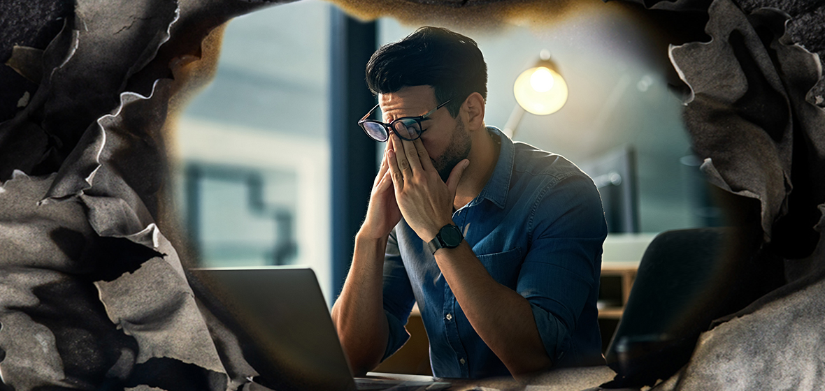 An office worker rubs his eyes after too many long days at work.