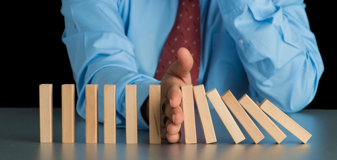 Man's hand stoping a set of dominos