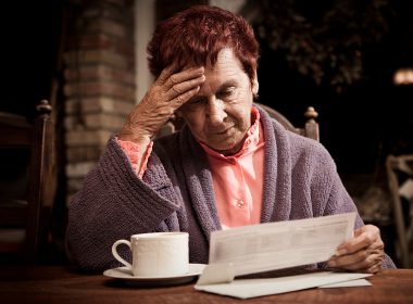 Distressed senior looking at bills on desk