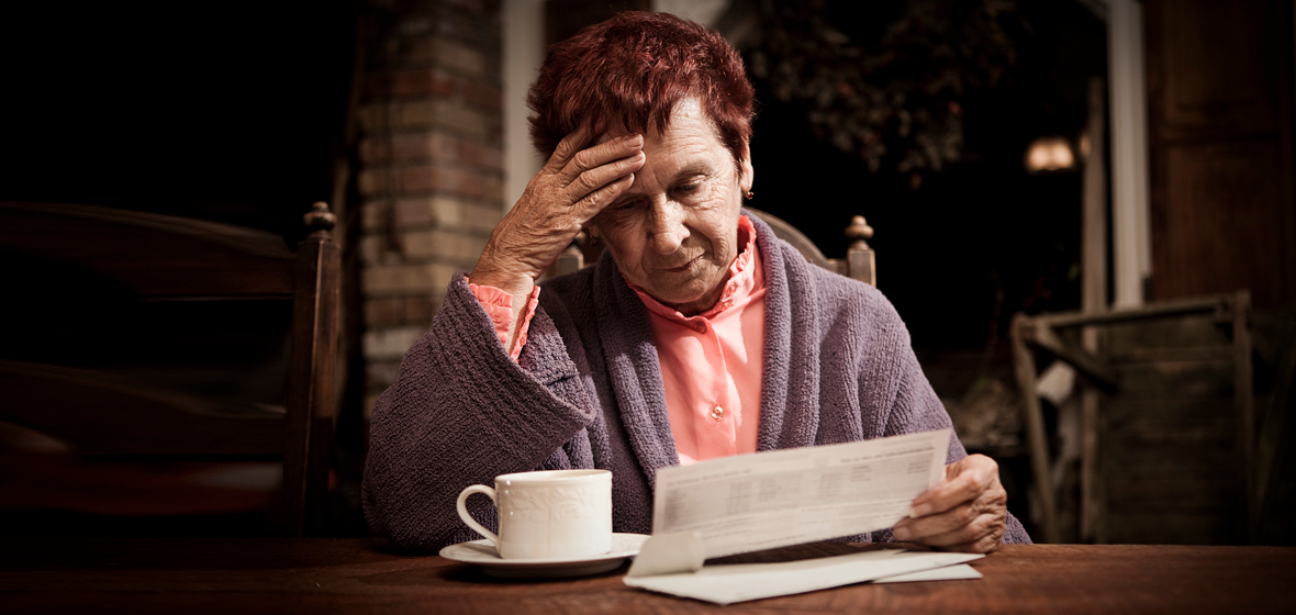 Distressed senior looking at bills on desk