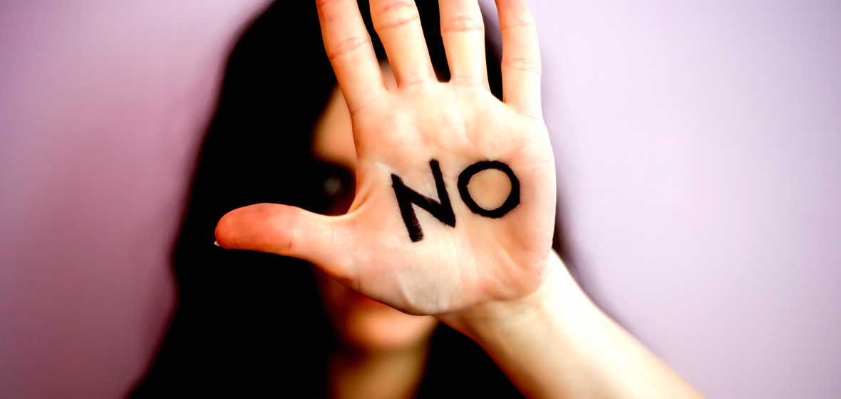 Woman holds a hand up with the word 'No' written on her palm