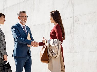 Man shakes a woman's hand outside a building