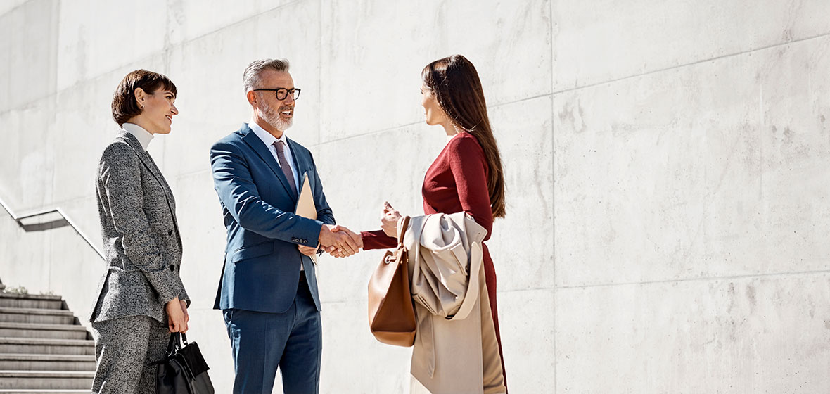 Man shakes a woman's hand outside a building