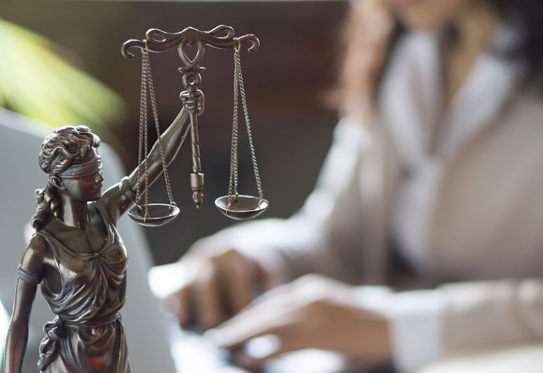 Lady Justice statue next to a woman's laptop
