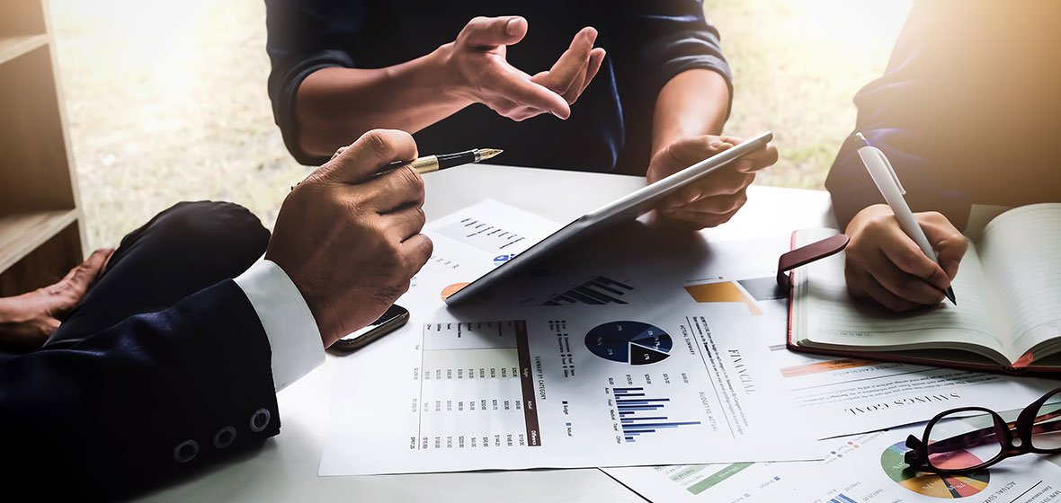 Three people review documents at a desk