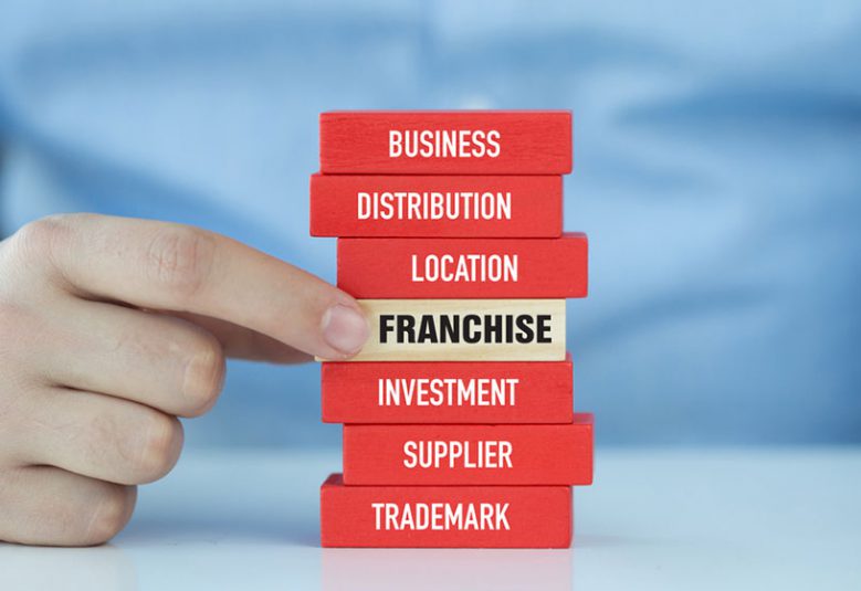 Blocks of wood with words business, distribution, location, franchise, investment, supplier, trademark on the sides