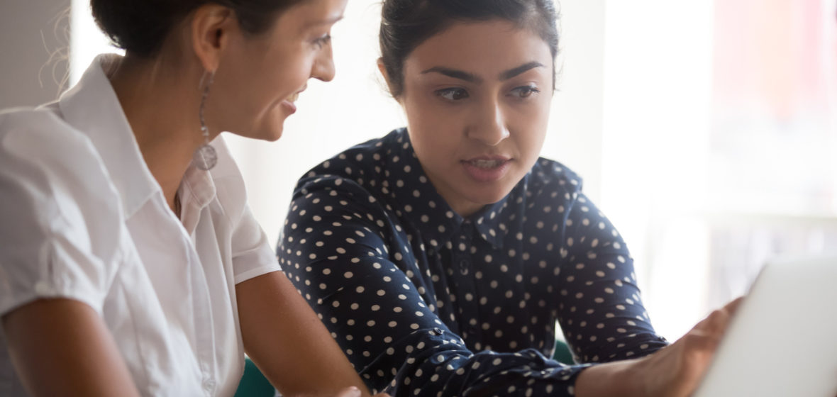 older and younger women in discussion at desk