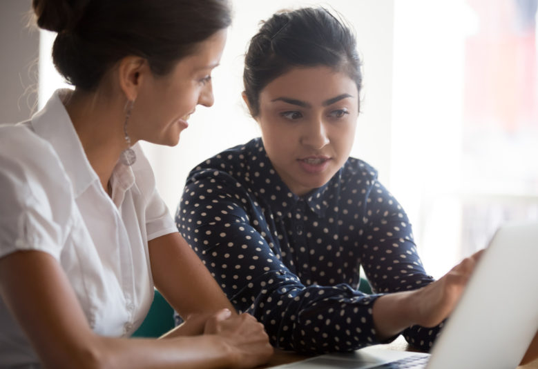 older and younger women in discussion at desk