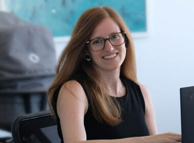 photo of lawyer Rafaella at her desk with baby pram in the background to show she is on parental leave