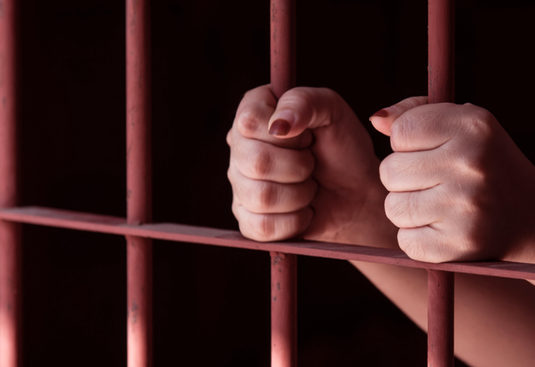 photo of women's hands behind bars to show women in prison