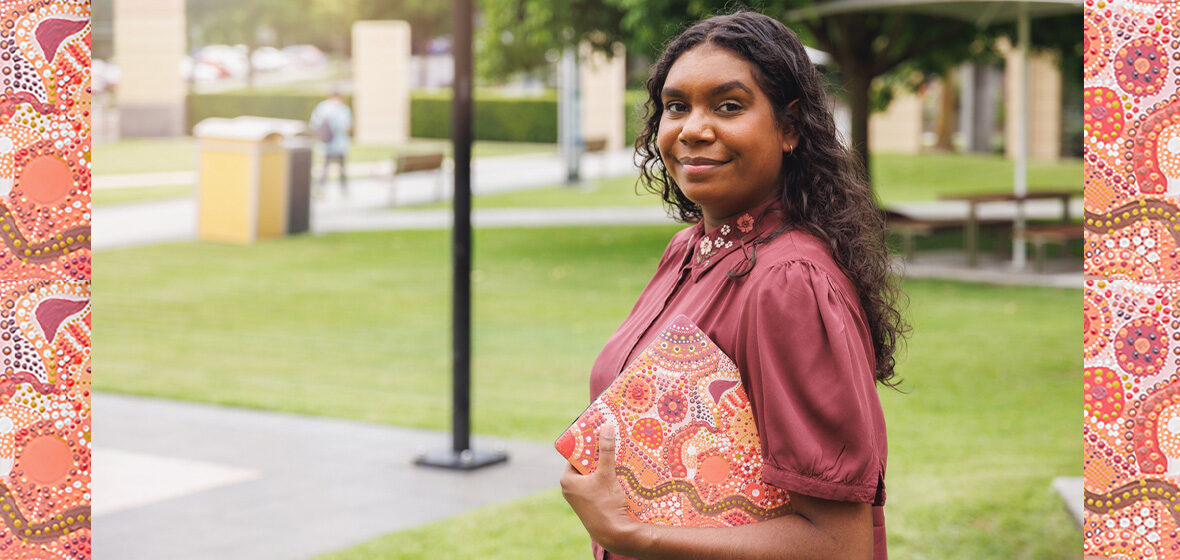 image showing young Aboriginal woman holding folder standing outdoors, to illustrate First Nations Cadetship Program