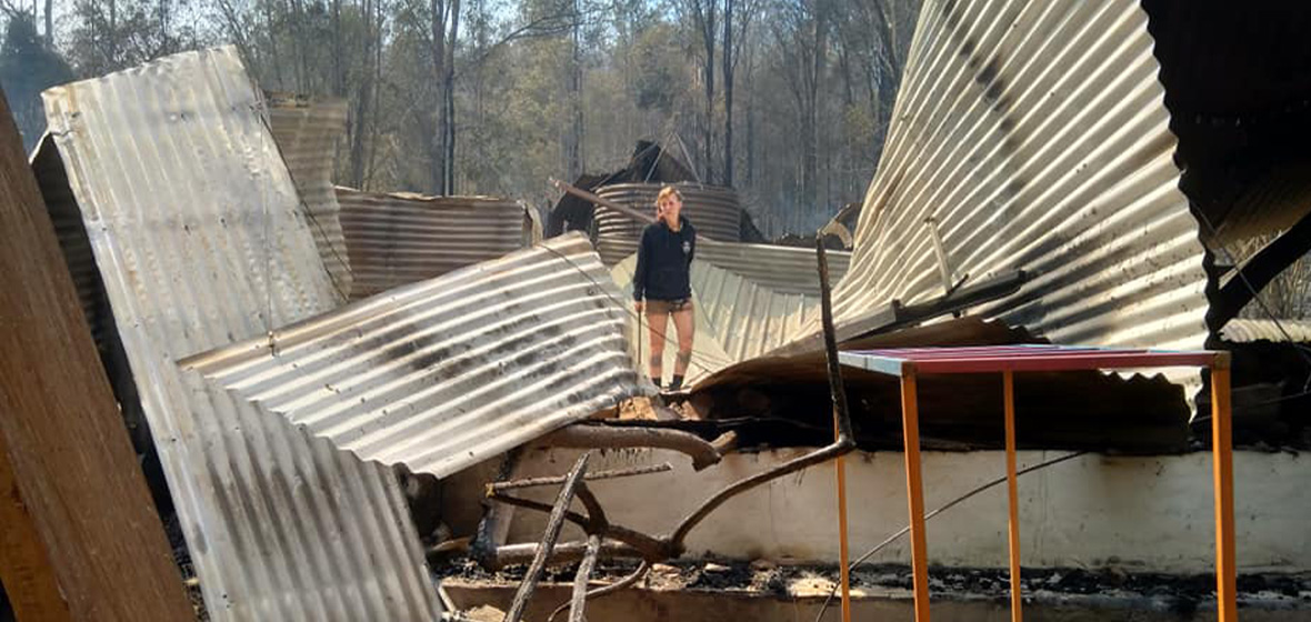 [image] photo of bushfire survivor with burned house