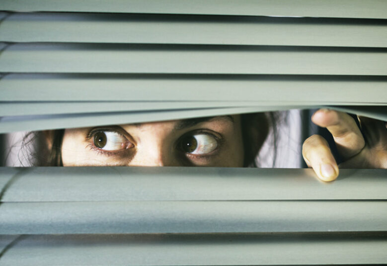 photo of woman peering through blinds