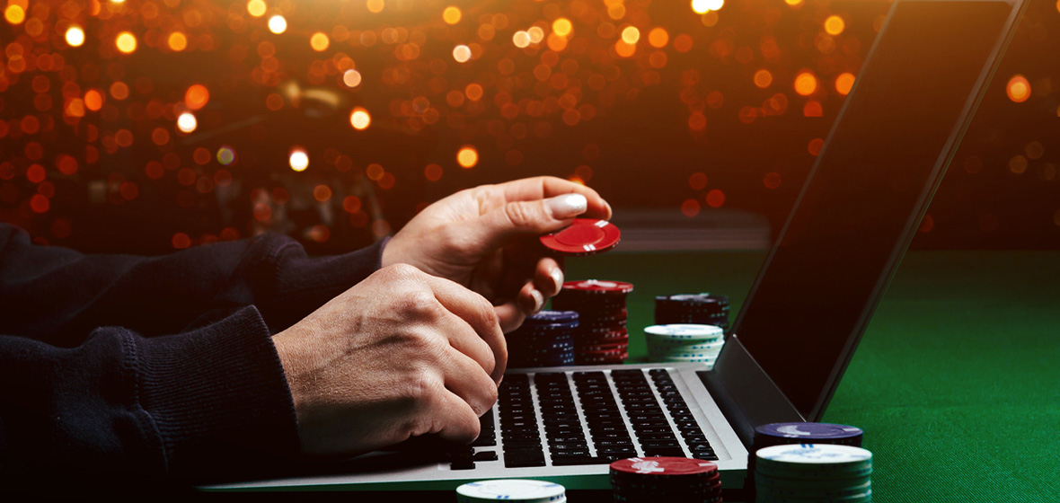 photo of hands playing poker on a card table in front of a computer to show online gambling
