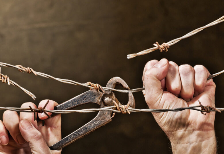 photo of hands cutting barbed wire to symbolise end to indefinite detention