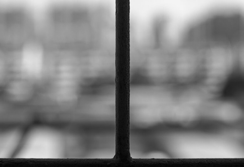 photo of barred window with grey scenery outside to depict poor mental health of prisoners